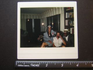   Polaroid 0583 black lady in hat, white man w phone, black man goofy