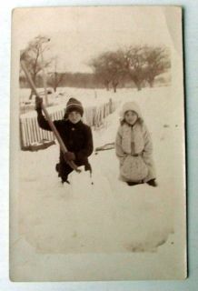 RPPC POSTCARD TWO CHILDREN PLAYING IN SNOW WITH SHOVEL